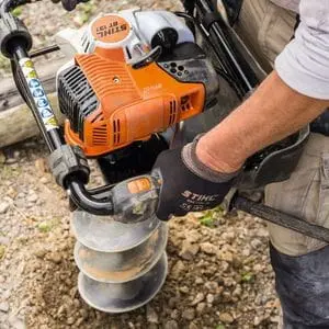 a close up of someone using the STIHL BT 131 Petrol Earth Auger to drill a hole in stony ground