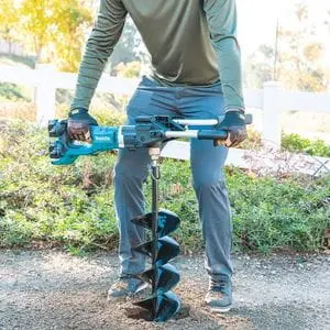 a man using the Makita DDG460ZX7 Twin 18v LXT Earth Auger BL to dig a hole in the ground