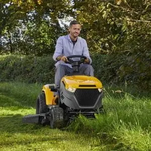 a man cutting grass near a hedgerow, using the STIGA Tornado 5108 W Petrol Garden Tractor