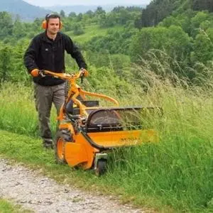 a man using the AS MOTOR AS 701 SM Walk-Behind Flail Mower to cut very long grass on the side of a countryside path