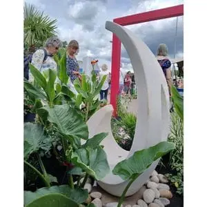 a curved water feature on a bed of stones, surrounded by foliage, with a square, pink arch in the background - part of Dakic Garden Design's The Heart of the Jungle garden