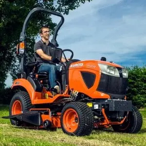 a man mowing grass using a Kubota BX231 Compact Tractor