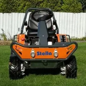 the Stella Racoon 95 4×4 Ride-On Flail Mower on a lawn, in front of a white fence and trees