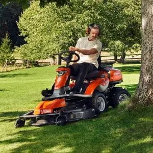 a man wearing ear defenders, mowing around the base of a tree using the Husqvarna R 316TsX AWD Petrol Rider