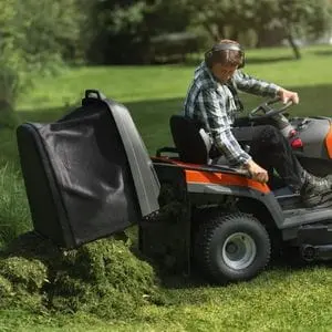 a man operating the low-dump grass collector on a Husqvarna garden tractor
