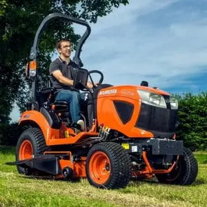 a man mowing a field using the Kubota BX231 Compact Tractor