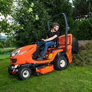 a man sat in the driver's seat of a Kubota GR Series garden tractor, depositing grass clippings from the collector onto the edge of a lawn