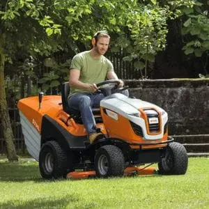 a man wearing ear defenders, mowing a lawn using the STIHL RT 6127 Petrol Ride-on Lawn Mower