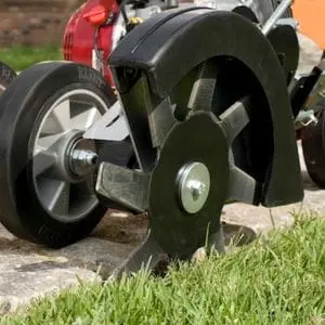 a lawn edger cutting grass next to a path