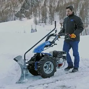 a man clearing snow from a field using the BCS 706 PowerSafe®2 Wheel Tractor with snow blade attachment