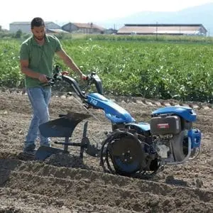 a man cultivating soil on a farm using the BCS 740 Two Wheel Tractor