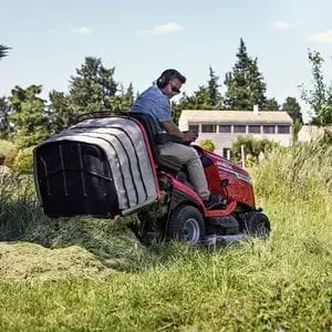 a man emptying a Honda HF Ride-On Mower's grass collector from the driver's seat