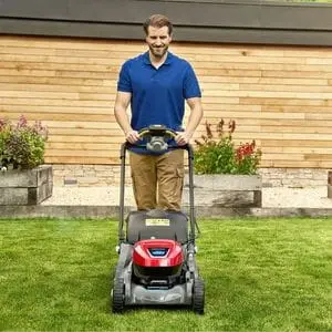 a satisfied-looking man mowing a lawn with a Honda HRX Lawnmower