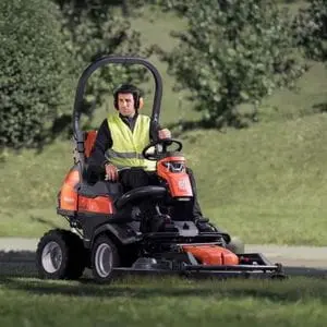 a man wearing a high-visibility jacket and ear defenders, mowing parkland using the Husqvarna P 524X EFI Out Front Mower