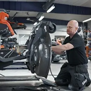 a Husqvarna servicing technician, carrying out work on a ride-on mower's cutting deck
