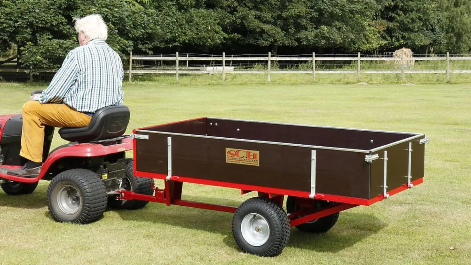 a man on a ride-on mower, towing the SCH GWTS15 Trailer across a lawn