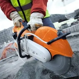 a close up of a man cutting grey stone on a building site, using the STIHL TS 410 Petrol Cut-off Machine