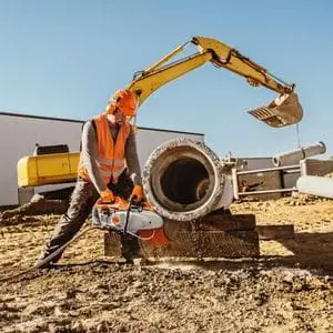 a man on a building site, cutting through the underside of a large pipe using the STIHL TS 440 Petrol Cut-off Machine