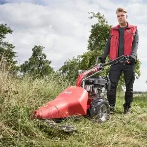 a man cutting long grass using the AL-KO COMBI BF 5002-R Two Wheel Tractor with scythe mower attachment