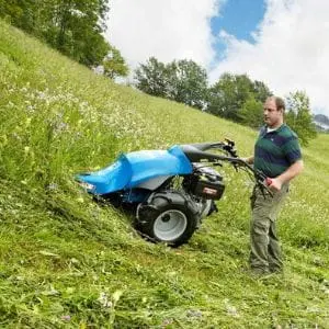a man cutting long grass on a slope using the BCS 706 Petrol Rotavator with Laser Cutter Bar attachment