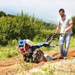 a man preparing soil at the edge of a field using the BCS 706 Petrol Rotavator with Rotary Hoe attachment
