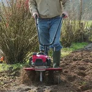 a man cultivating soil using the Honda FG205 Petrol Mini Tiller
