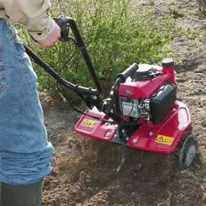 a shot taken from behind someone cultivating soil using the Honda FG205 Petrol Mini Tiller